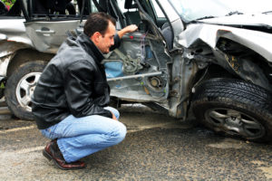 photo of a guy inspecting the damaged car